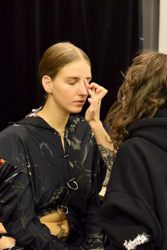 woman doing makeup to model in studio